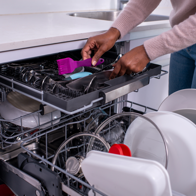 A person loads a dishwasher