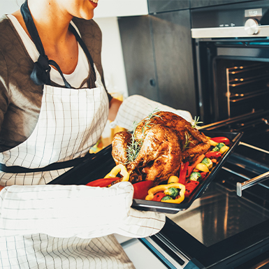 Woman removing chicken from oven