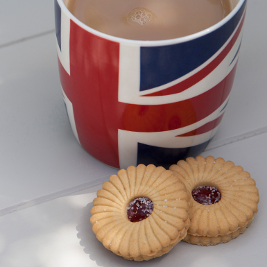 A cup of tea in a UK Flag mug with two biscuits